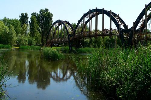 a bridge over a river with a reflection in the water at ZÁMOR HOLIDAY HOUSE in Keszthely