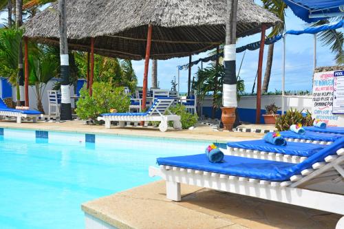 a swimming pool with blue lounge chairs and an umbrella at Ocean View Nyali Boutique Hotel in Nyali