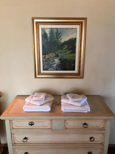 a painting above a dresser with towels on it at Villa Bonelli Bed & Fest in Savigliano