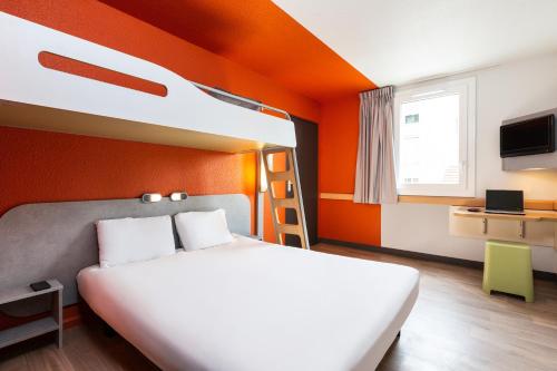 een slaapkamer met een bed met een oranje muur bij ibis budget Paris Porte de Vincennes in Parijs