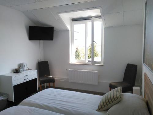 a bedroom with a bed and two chairs and a window at Hotel De Wilde Kriek in Valkenburg