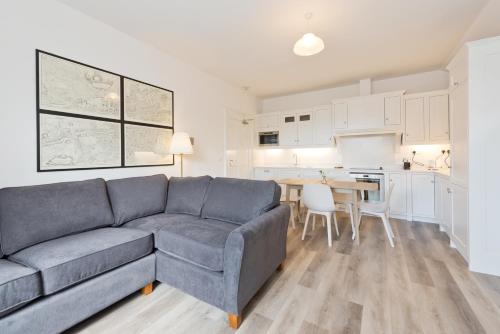 a living room with a gray couch and a kitchen at Henrietta Suites City Centre in Dublin