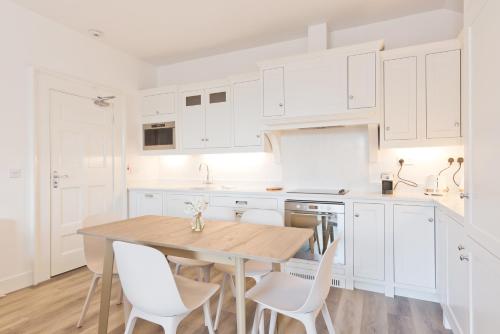 a kitchen with white cabinets and a wooden table and chairs at Henrietta Suites City Centre in Dublin