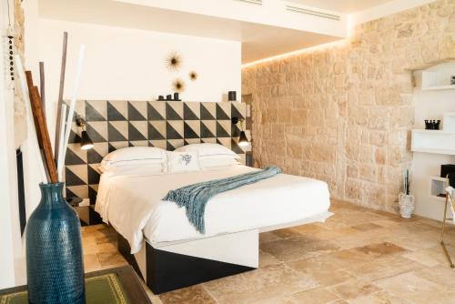 - une chambre avec un grand lit blanc et un mur en briques dans l'établissement Antico Mondo Rooms & Suites, à Polignano a Mare