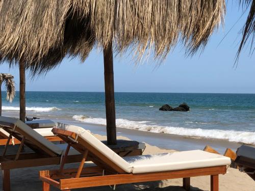 a group of chairs and umbrellas on a beach at El Samay Hotel Boutique in Canoas De Punta Sal