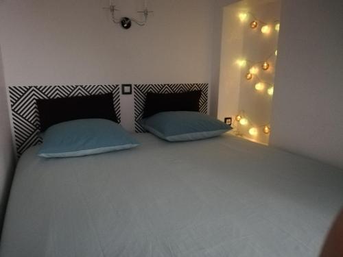 a bedroom with a bed with two pillows and lights at La Bonbonnière de Salomé Hyper centre parking possible in Rouen