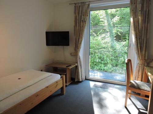 a bedroom with a bed and a large window at Hotel Bergische Schweiz in Velbert