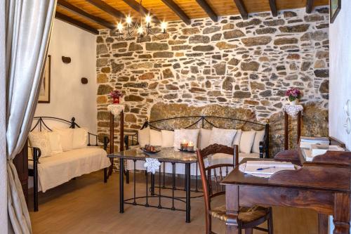 ein Wohnzimmer mit einem Tisch und einer Steinmauer in der Unterkunft Fimaira in Ermoupoli