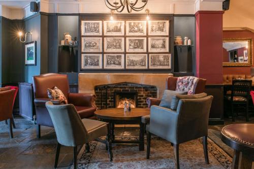 a room with a fireplace and chairs and a table at Rose And Crown Hotel in London