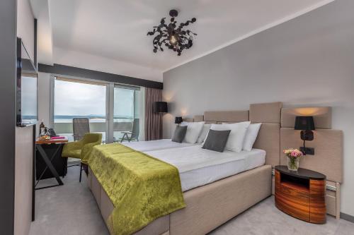 een slaapkamer met een bed, een bureau en een raam bij Hotel Omorika in Crikvenica