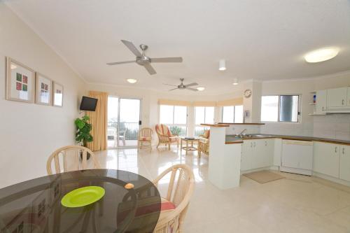 cocina y comedor con mesa y sillas en Pacific Waves Apartments, en Noosa Heads