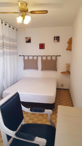 een slaapkamer met een wit bed en een stoel bij T2 in Gruissan