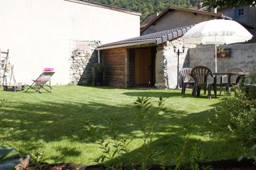 un patio con mesa, sillas y sombrilla en Gite de l'Amistat, en Vicdessos