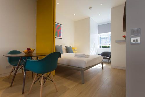 1 dormitorio con 1 cama, mesa y sillas en NoHo 132 Serviced Apartments by Concept Apartments en Londres