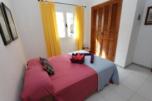 Un dormitorio con una cama rosa con una cesta. en Apartment overlooking to the pool 2450, en La Mata