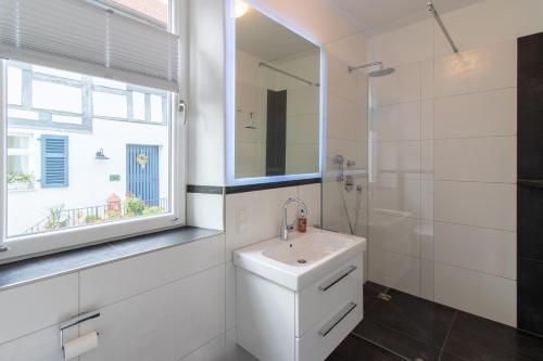ein weißes Bad mit einem Waschbecken und einem Fenster in der Unterkunft Exklusive Ferienwohnung Geisfeld in Geisfeld