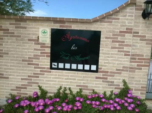 a sign on the side of a brick wall with flowers at Agriturismo bio Verde Armonia in Montemarciano