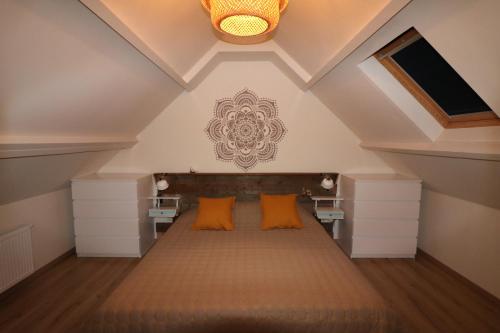 a attic bedroom with a bed with orange pillows at De Strandmus in Egmond aan Zee