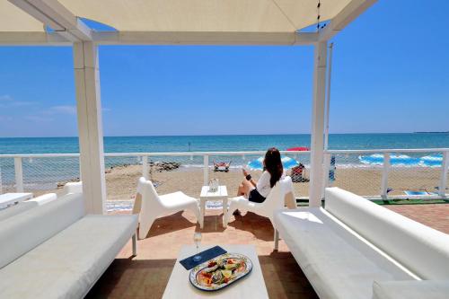 a woman sitting in a chair at the beach at Le Palme Village in Terracina