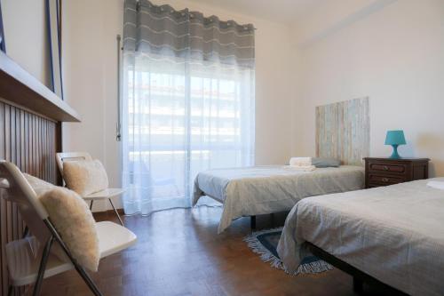 a bedroom with two beds and a chair and a window at Figueira da Foz Sunset Apartment in Figueira da Foz