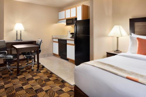 a hotel room with a bed and a desk and a kitchen at Hawthorn Suites By Wyndham Oak Creek/Milwaukee Airport in Milwaukee