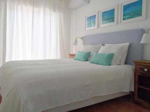 um quarto com uma cama branca e 2 almofadas azuis em IM On Luz Arte em Luz