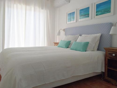 a bedroom with a white bed with two blue pillows at IM On Luz Arte in Luz