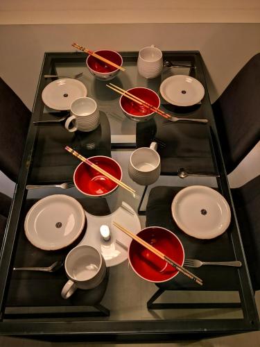 a glass table with red and white plates and chopsticks at Strait Garden Suites X Ace Pro @ George Town in Jelutong