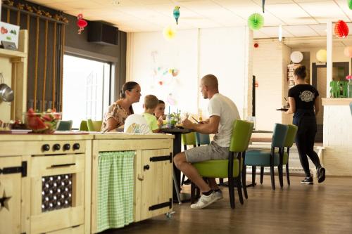 un grupo de personas sentadas en una mesa en una cocina en Camping Scheldeoord en Baarland