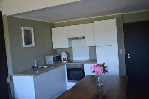 une cuisine avec des placards blancs et un vase de fleurs sur une table dans l'établissement le dépot 2 appartement 406, à Malmedy