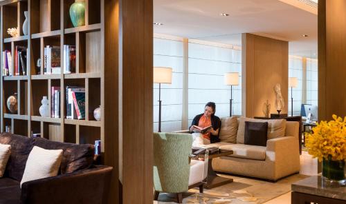 a woman sitting on a couch in a living room at Fraser Suites Guangzhou in Guangzhou