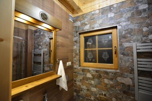 a bathroom with a stone wall and a mirror at Smreco House in Zakopane