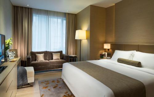 a hotel room with a large bed and a couch at Fraser Suites Guangzhou in Guangzhou