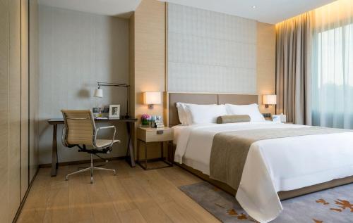 a bedroom with a bed and a desk and a chair at Fraser Suites Guangzhou in Guangzhou