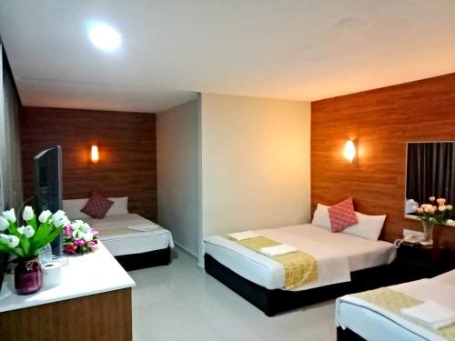 two beds in a hotel room with flowers on the counter at Eazy Hotel at Ampang in Batu Empat