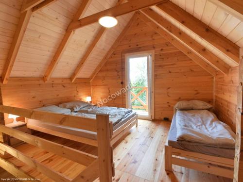 Ustronne Domki في أوستروني مورسكي: غرفة نوم بسريرين في كابينة خشب