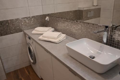 a bathroom with a sink and a washing machine at Apartament Srebrny z garażem in Kołobrzeg
