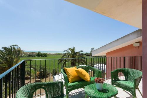 a balcony with green chairs and a table with a yellow pillow at Al Ficodindia in Sampieri