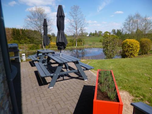 two picnic tables with umbrellas next to a pond at Oxygen House, Holiday and Team building in Ovifat