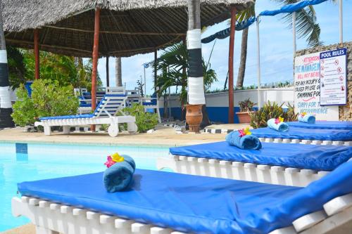 a pool with three blue tables with hats on them at Ocean View Nyali Boutique Hotel in Nyali
