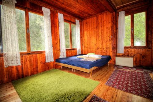una camera da letto con letto in una camera in legno con finestre di Chata Zlatka a Spišské Tomášovce