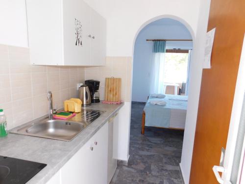 una cucina con lavandino e una camera con letto di Evgenios Studios ad Agios Georgios Pagon
