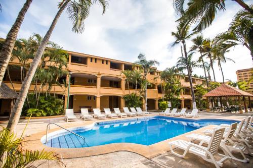 a resort pool with lounge chairs and palm trees at Hotel Margaritas in Mazatlán