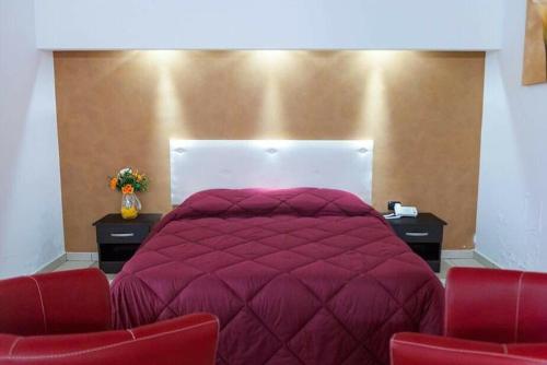 a bedroom with a large purple bed with two red chairs at Hotel 660 in Bisignano
