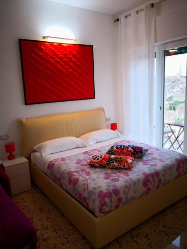 a bedroom with a bed with a red painting on the wall at Dimore Pietrapenta Apartments, Suites & Rooms - Via Lucana 223, Via Piave 23, Via Chiancalata 16, Vico Fornaci 9 in Matera