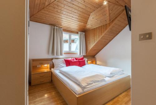 ein kleines Schlafzimmer mit einem Bett mit roten Kissen in der Unterkunft Gasthof Hanni in Meran