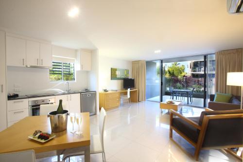 a kitchen and living room with a table and a dining room at Ramada by Wyndham Hervey Bay in Hervey Bay