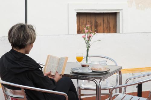 a person sitting at a table reading a book at Pensión San Marcos in Arcos de la Frontera
