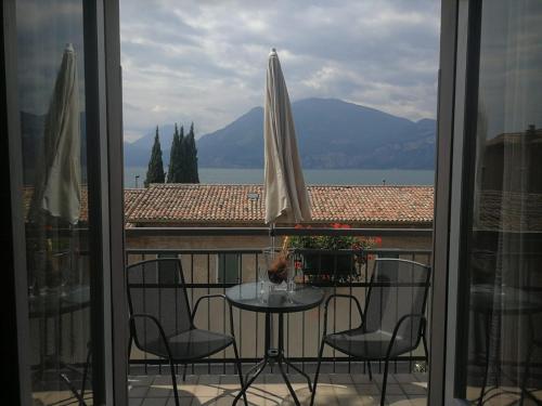 a balcony with a table with chairs and an umbrella at Albergo Al Pescatore in Brenzone sul Garda
