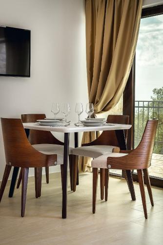 a dining table and chairs with wine glasses on it at Adria Lux Apartments Sveti Stefan in Budva